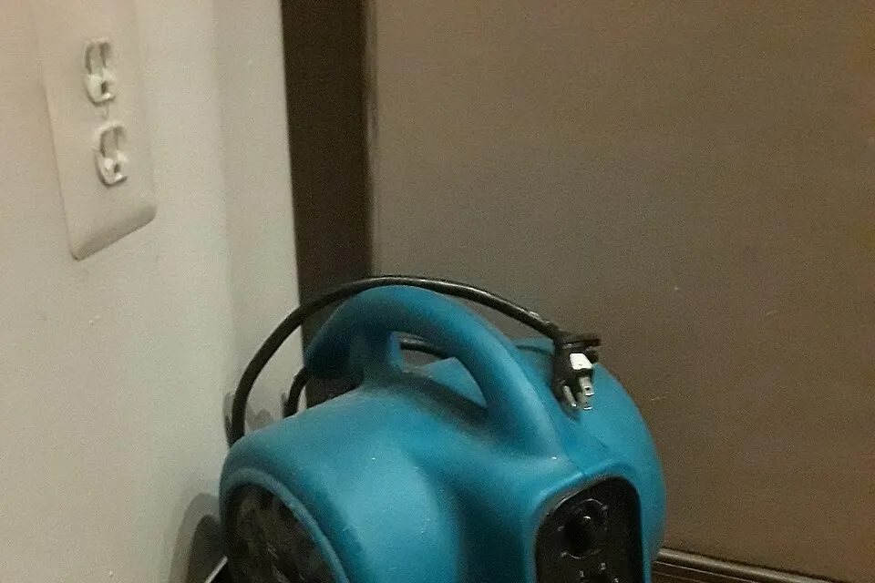 Portable air mover beside an interior wall